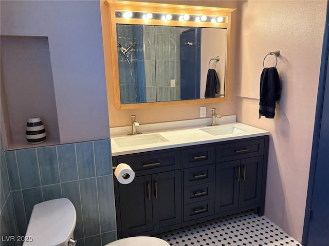 bathroom featuring a sink, tile walls, toilet, and double vanity