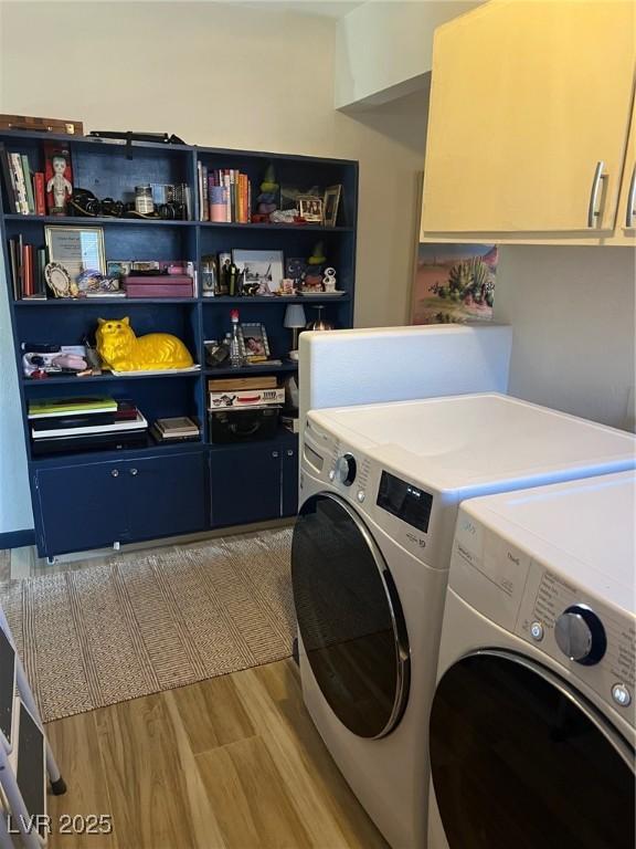 washroom with cabinet space, light wood-style flooring, and washing machine and clothes dryer