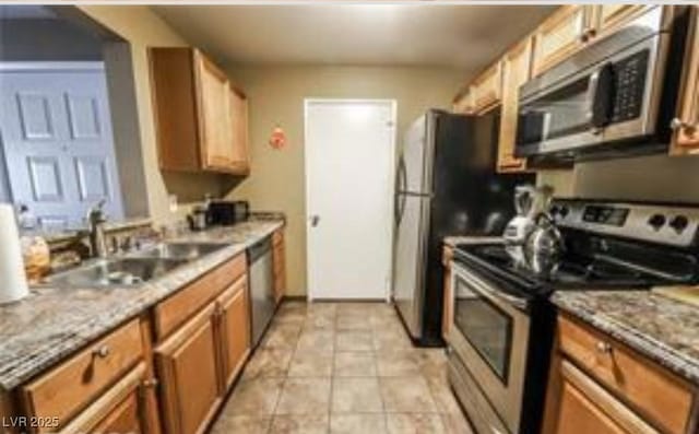 kitchen featuring appliances with stainless steel finishes, light stone countertops, sink, and light tile patterned floors