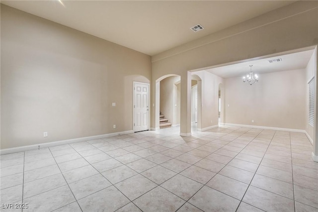 spare room with a chandelier and light tile patterned floors