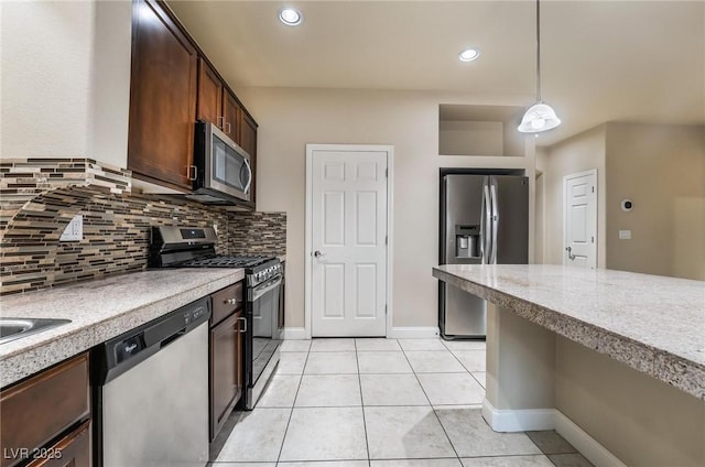 kitchen with tasteful backsplash, hanging light fixtures, light tile patterned floors, stainless steel appliances, and dark brown cabinets