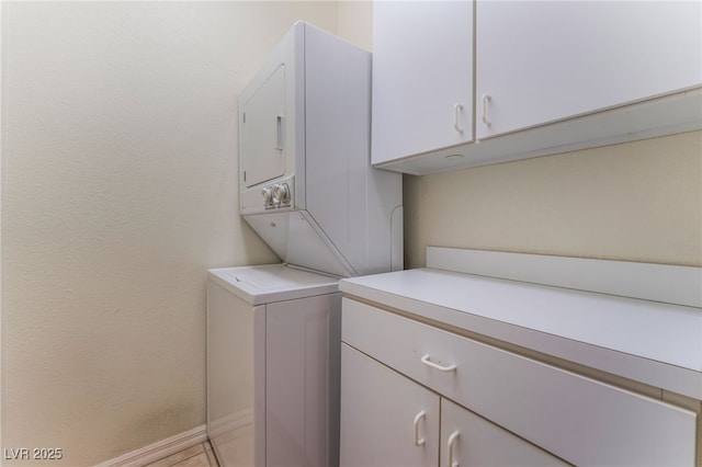 washroom featuring cabinets and stacked washer and clothes dryer