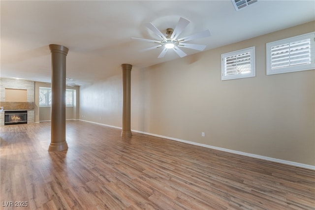 unfurnished living room with ornate columns, hardwood / wood-style floors, a fireplace, and ceiling fan