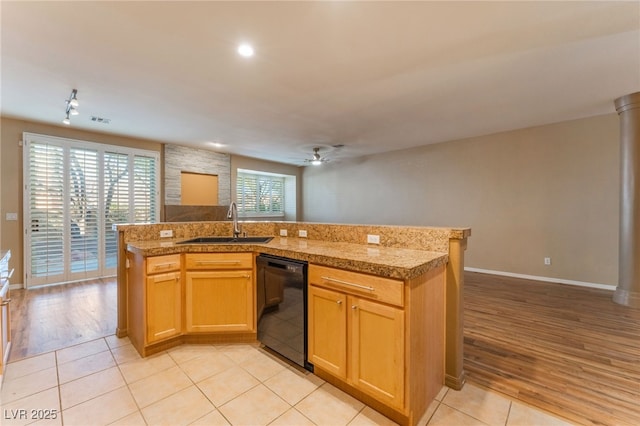 kitchen featuring sink, light tile patterned floors, black dishwasher, ceiling fan, and a kitchen island with sink