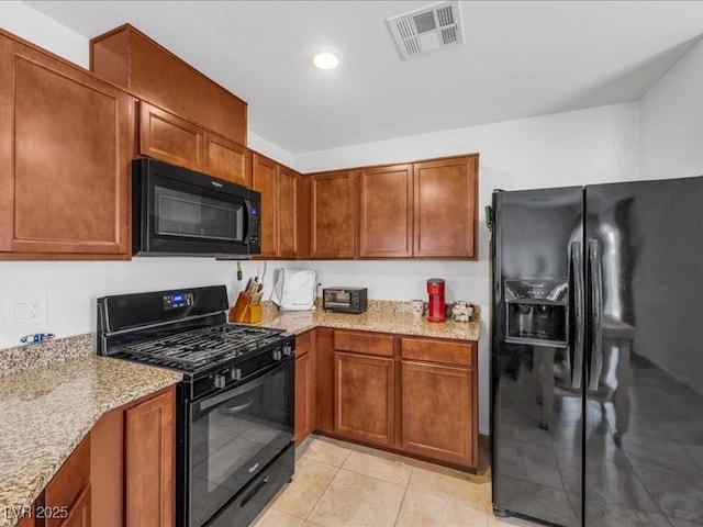 kitchen with light stone counters, black appliances, and light tile patterned flooring