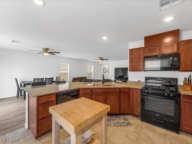 kitchen featuring black appliances, sink, light tile patterned floors, light stone counters, and kitchen peninsula