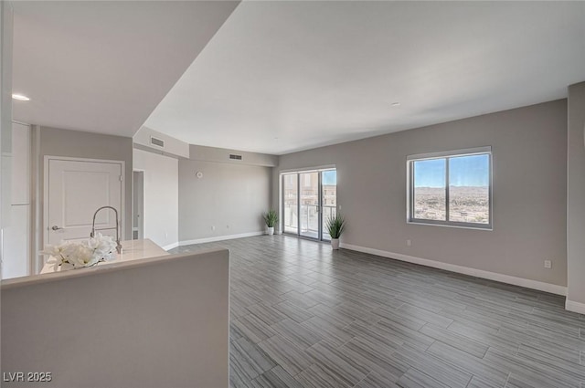 unfurnished living room featuring visible vents, light wood-style flooring, and baseboards