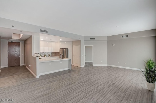 unfurnished living room with visible vents and baseboards