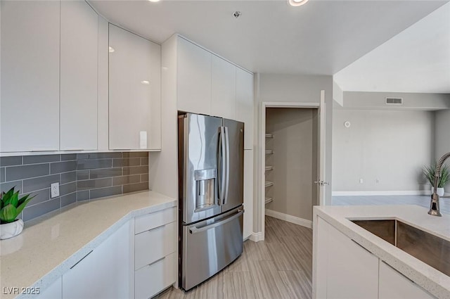 kitchen featuring tasteful backsplash, visible vents, white cabinets, and stainless steel fridge with ice dispenser