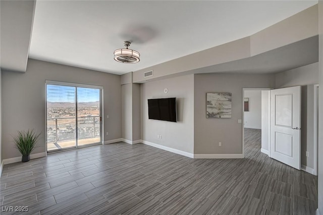 unfurnished living room featuring wood tiled floor, visible vents, and baseboards