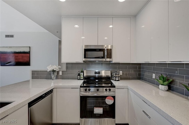 kitchen featuring appliances with stainless steel finishes, white cabinetry, decorative backsplash, and modern cabinets