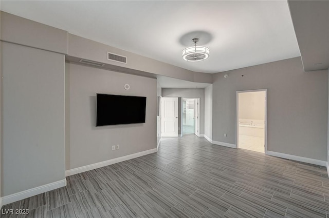 unfurnished living room with wood tiled floor, visible vents, and baseboards