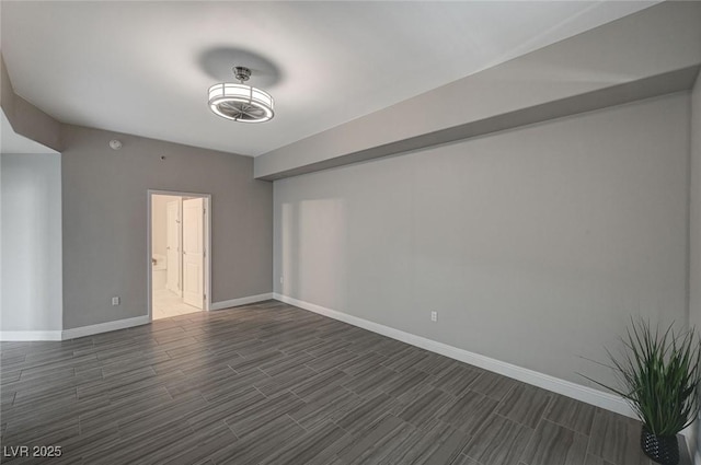 spare room with baseboards and wood finish floors