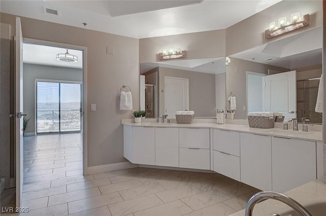 bathroom with double vanity, a sink, and baseboards