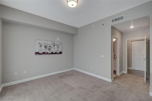 unfurnished room featuring light colored carpet, visible vents, and baseboards