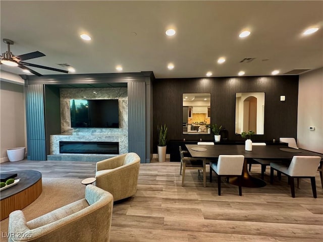 interior space featuring visible vents, light wood-type flooring, a high end fireplace, and recessed lighting