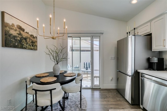 dining space featuring dark wood-type flooring, lofted ceiling, and a notable chandelier