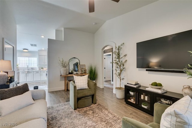 living room with lofted ceiling, ceiling fan, and light hardwood / wood-style flooring