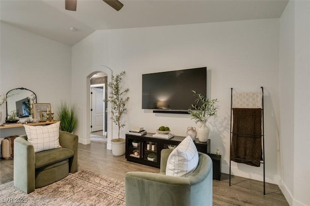 living room featuring wood-type flooring, ceiling fan, and vaulted ceiling