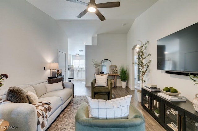 living room featuring sink, light hardwood / wood-style flooring, ceiling fan, and vaulted ceiling