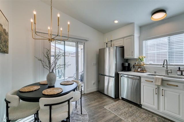 kitchen with sink, appliances with stainless steel finishes, a notable chandelier, a wealth of natural light, and white cabinets