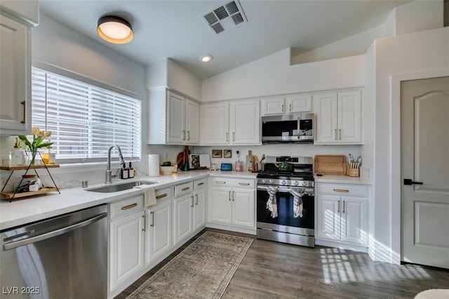 kitchen with lofted ceiling, sink, dark hardwood / wood-style floors, stainless steel appliances, and white cabinets