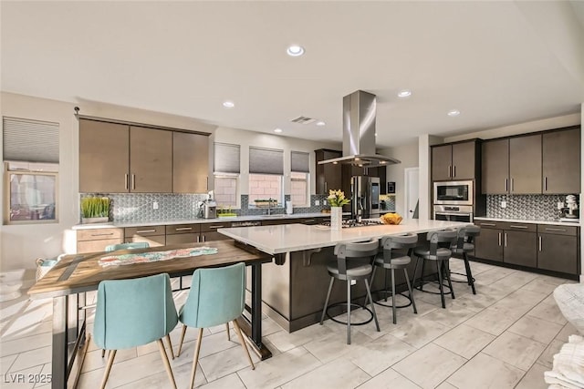 kitchen featuring sink, backsplash, stainless steel appliances, a center island, and island range hood