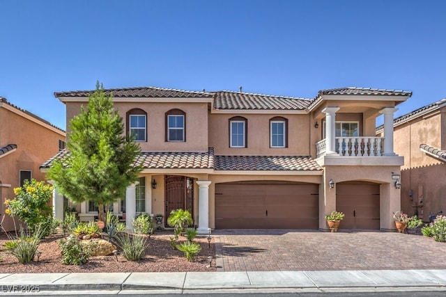 mediterranean / spanish home featuring stucco siding, an attached garage, a tile roof, and decorative driveway