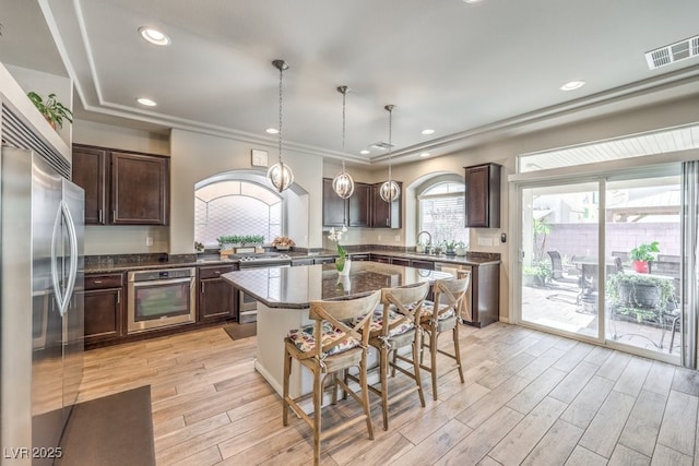 6461 Mount Eden Ave, Las Vegas, NV 89139 - kitchen with dark brown cabinets, light wood-style floors, stainless steel appliances, and pendant lighting