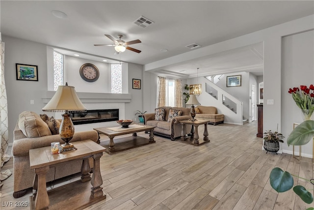 6461 Mount Eden Ave, Las Vegas, NV 89139 - living area with a glass covered fireplace, stairway, light wood-style flooring, and visible vents