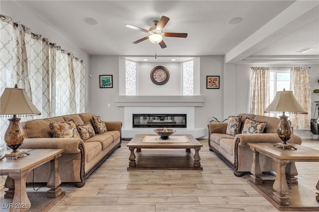 6461 Mount Eden Ave, Las Vegas, NV 89139 - living room featuring light wood-style floors, a ceiling fan, and a glass covered fireplace