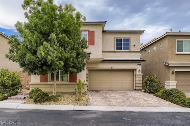 view of front facade featuring decorative driveway, an attached garage, and stucco siding