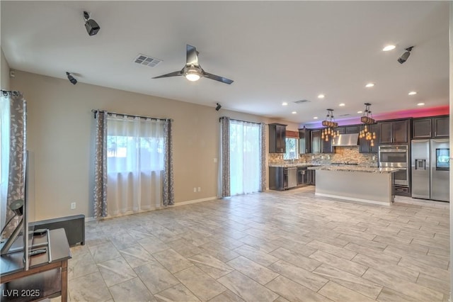 kitchen featuring visible vents, appliances with stainless steel finishes, open floor plan, a center island, and backsplash