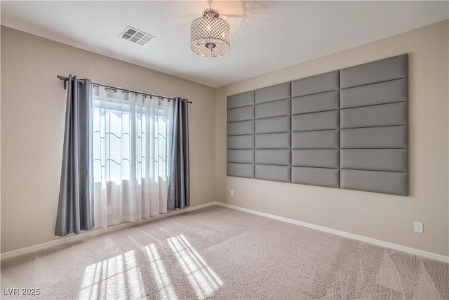 empty room with carpet, visible vents, and baseboards