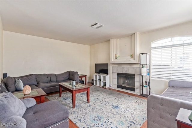 living room with a tiled fireplace and light hardwood / wood-style flooring