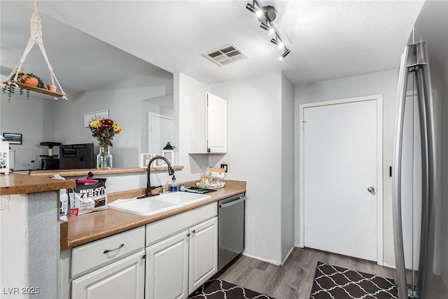 kitchen featuring white cabinetry, rail lighting, sink, stainless steel appliances, and dark wood-type flooring