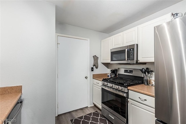 kitchen with stainless steel appliances, hardwood / wood-style floors, and white cabinets