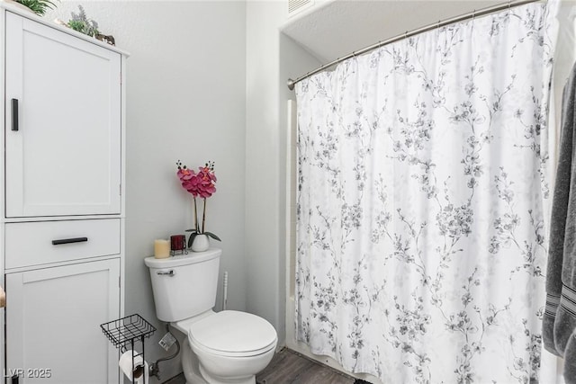 bathroom with toilet, curtained shower, and hardwood / wood-style floors