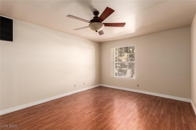 empty room with ceiling fan and dark hardwood / wood-style flooring