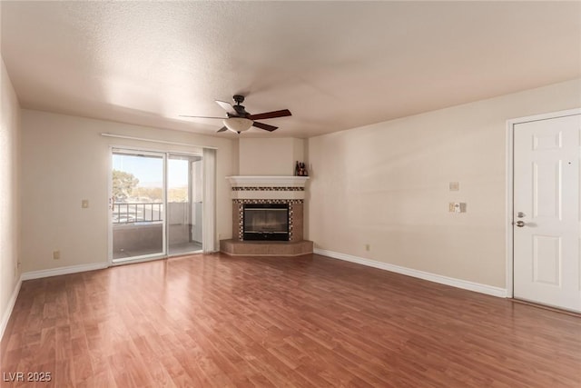 unfurnished living room with hardwood / wood-style flooring, ceiling fan, a fireplace, and a textured ceiling