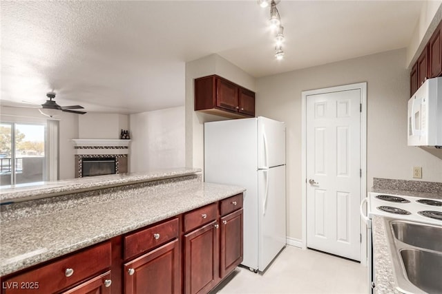 kitchen with a tiled fireplace, sink, white appliances, and ceiling fan