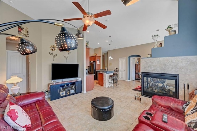 living room featuring a tile fireplace, light tile patterned floors, and ceiling fan