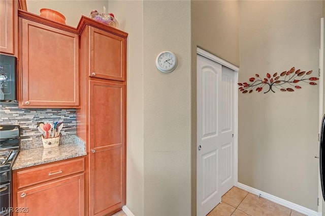 kitchen with tasteful backsplash, light tile patterned flooring, range, and light stone counters