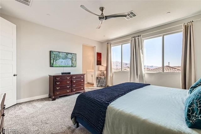 bedroom with ensuite bath, light colored carpet, and ceiling fan