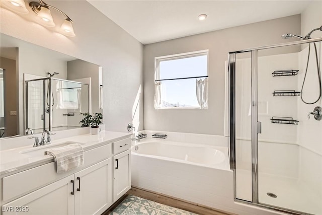 bathroom featuring plus walk in shower, wood-type flooring, and vanity