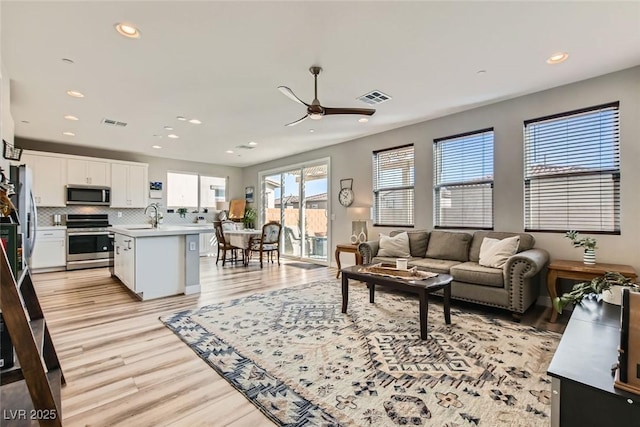 living room featuring ceiling fan, sink, and light hardwood / wood-style floors