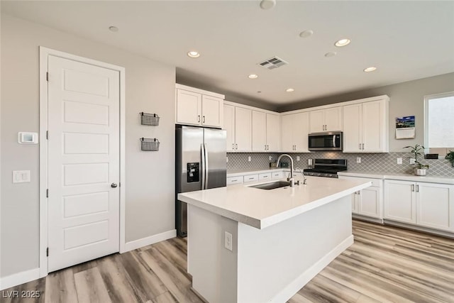 kitchen with appliances with stainless steel finishes, sink, a center island with sink, and white cabinets