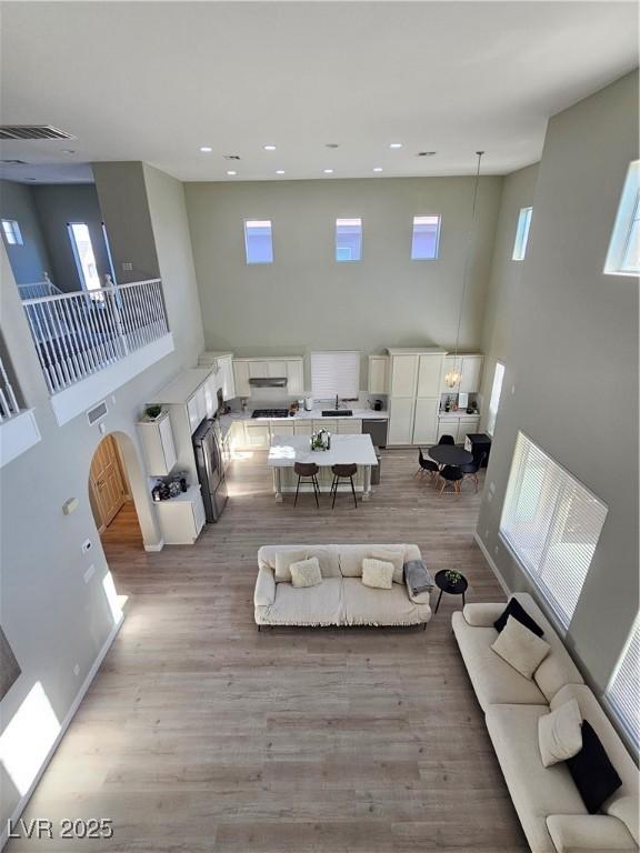 living room featuring a towering ceiling, plenty of natural light, and light hardwood / wood-style flooring