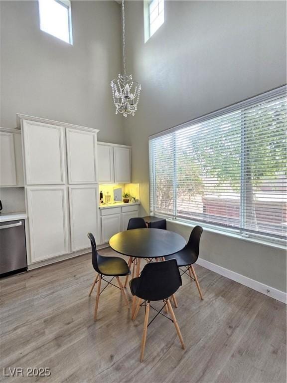 dining area featuring a towering ceiling, light hardwood / wood-style floors, and a chandelier