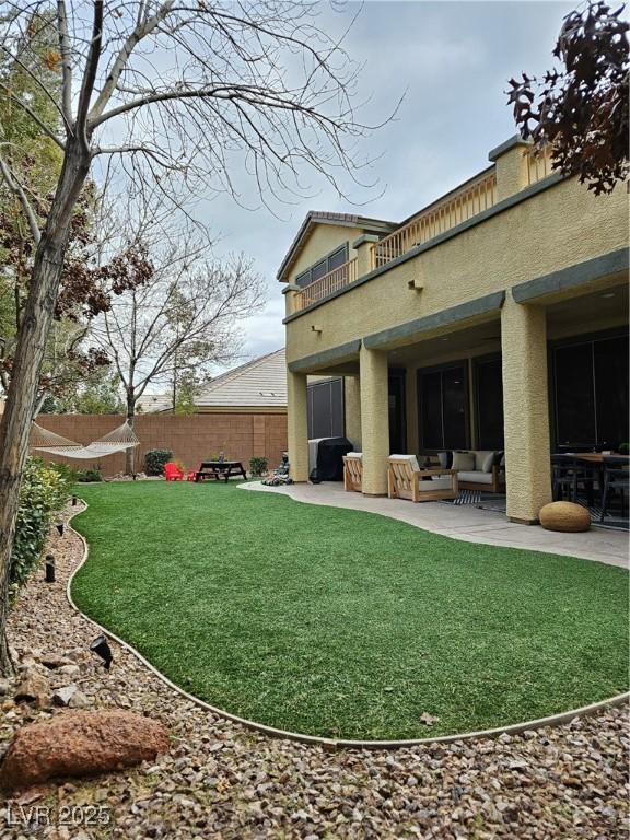 rear view of property with a balcony, a patio area, and a lawn